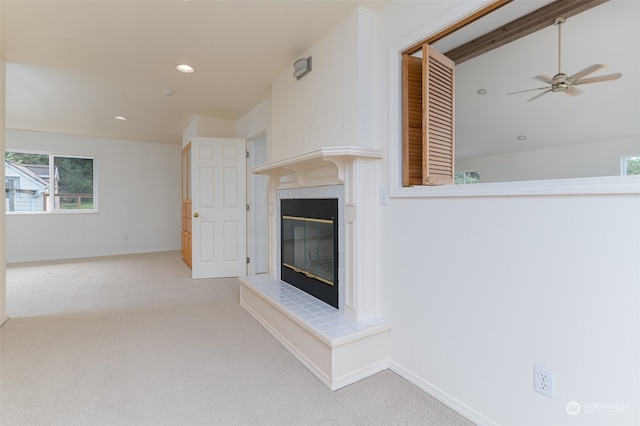 unfurnished living room featuring ceiling fan, a fireplace, and light colored carpet