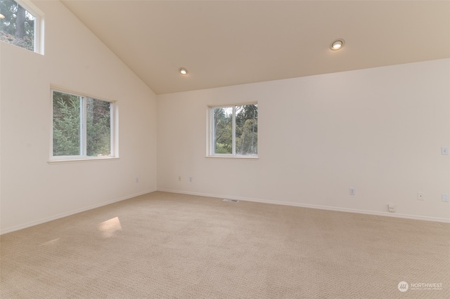 spare room featuring high vaulted ceiling and light carpet