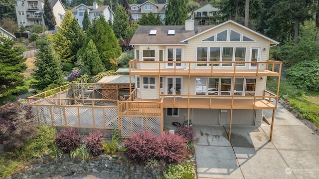 back of property with a deck, a balcony, and a garage