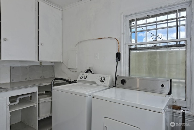 clothes washing area with washing machine and clothes dryer, crown molding, and cabinets