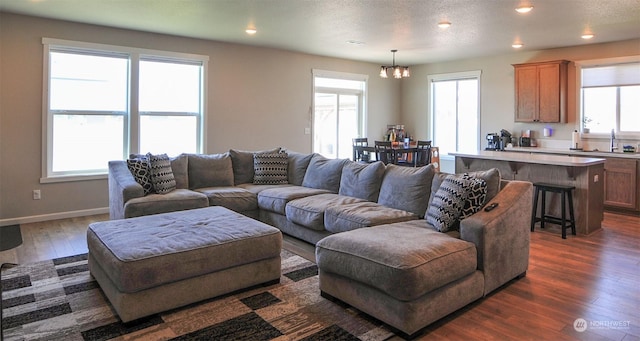 living area with baseboards, dark wood finished floors, recessed lighting, a notable chandelier, and a textured ceiling