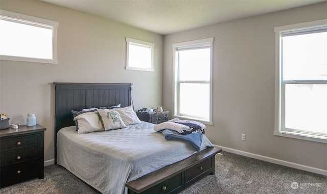 bedroom with dark colored carpet and baseboards