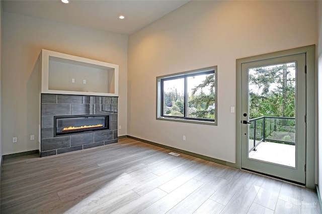 unfurnished living room with a tile fireplace and light wood-type flooring