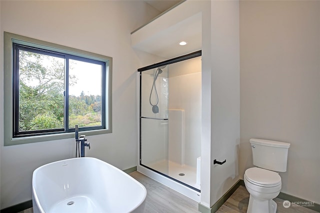 bathroom featuring wood-type flooring, plus walk in shower, and toilet