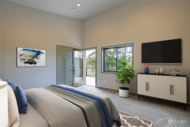 carpeted bedroom featuring access to outside and a high ceiling