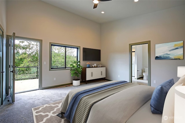 carpeted bedroom featuring a towering ceiling, access to outside, ceiling fan, and ensuite bathroom