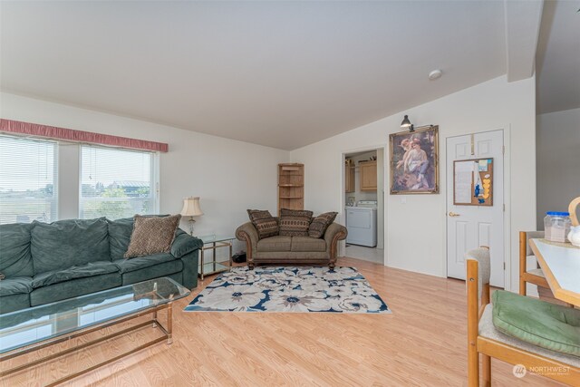 living room with washer / clothes dryer, lofted ceiling, and light wood-type flooring