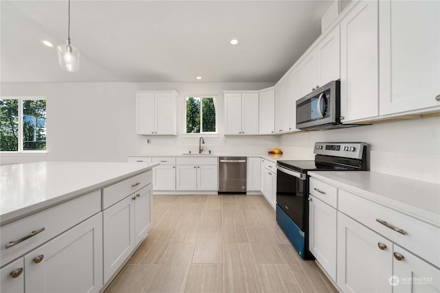 kitchen featuring a wealth of natural light, pendant lighting, stainless steel appliances, white cabinetry, and sink