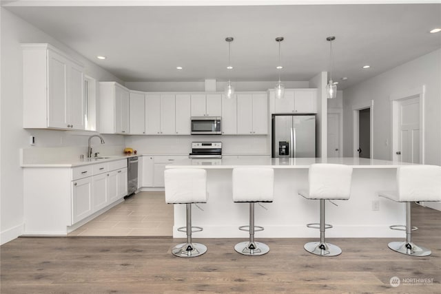 kitchen with a kitchen island, stainless steel appliances, white cabinets, and pendant lighting