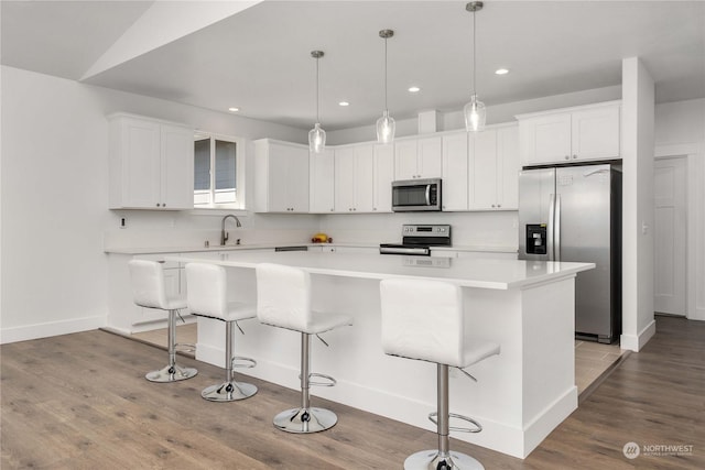 kitchen featuring a kitchen breakfast bar, stainless steel appliances, a center island, sink, and white cabinetry