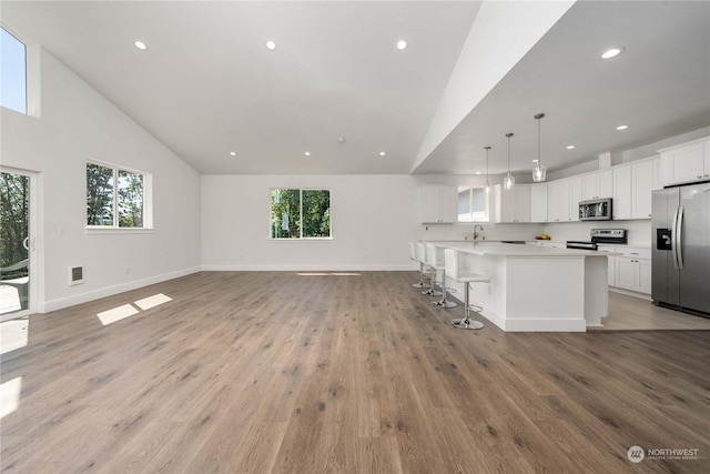 kitchen with stainless steel appliances, a kitchen island, decorative light fixtures, and white cabinetry