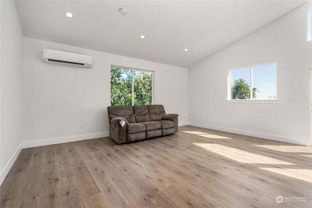 living area featuring a wall unit AC, lofted ceiling, and light hardwood / wood-style floors