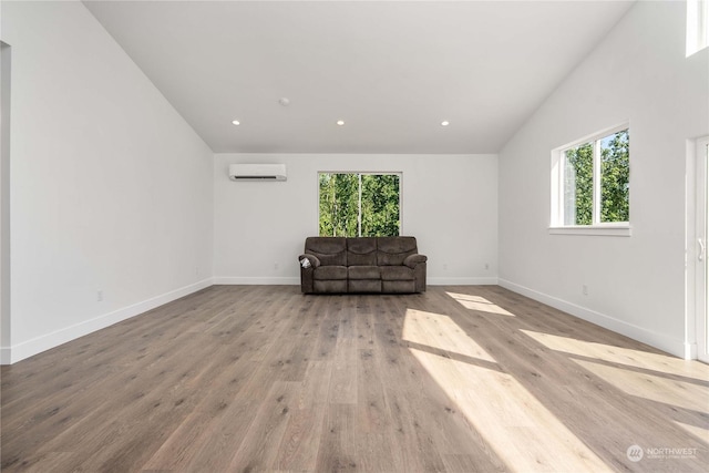 unfurnished room featuring light hardwood / wood-style floors, a wall mounted AC, and vaulted ceiling