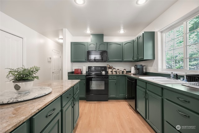 kitchen featuring light hardwood / wood-style flooring, green cabinetry, light stone countertops, sink, and black appliances