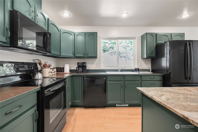 kitchen featuring light hardwood / wood-style flooring, light stone countertops, sink, green cabinets, and black appliances