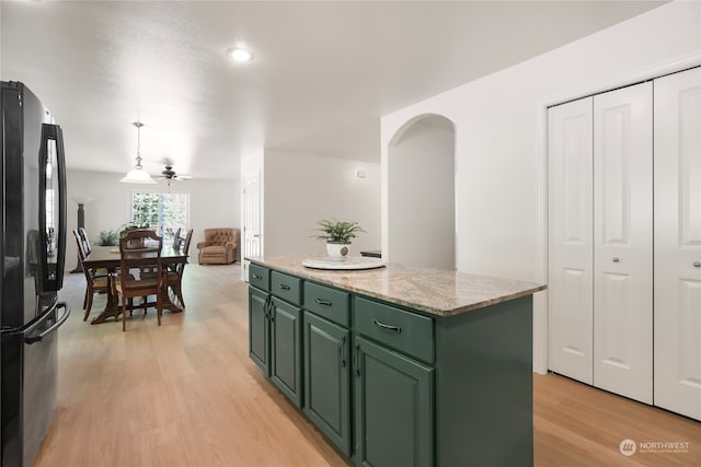 kitchen with a center island, black fridge, light wood-type flooring, ceiling fan, and green cabinetry