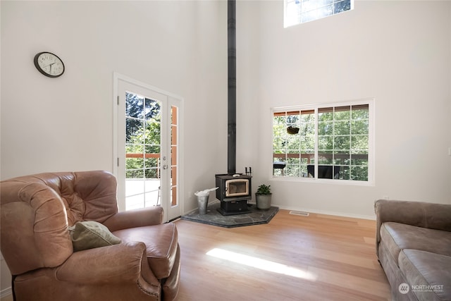 living room featuring a towering ceiling, light hardwood / wood-style floors, and a wood stove