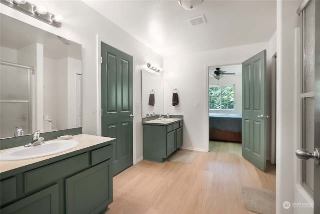 bathroom featuring ceiling fan, toilet, vanity, hardwood / wood-style floors, and walk in shower