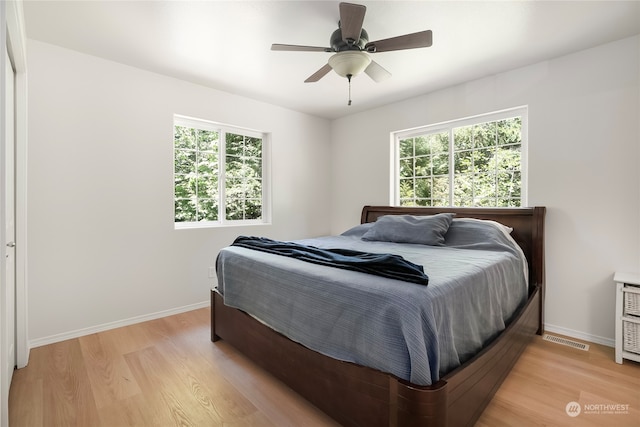 bedroom with ceiling fan, light hardwood / wood-style flooring, and multiple windows