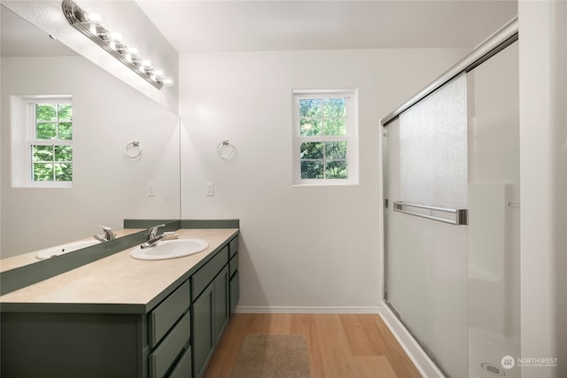 bathroom featuring a shower with door, a healthy amount of sunlight, and hardwood / wood-style flooring