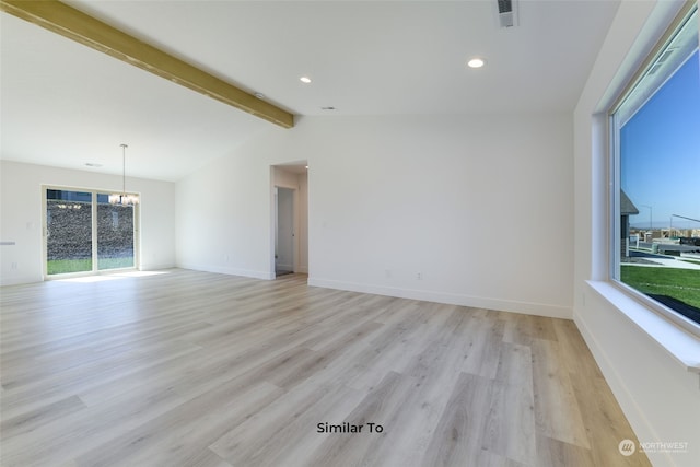 spare room featuring lofted ceiling with beams, a wealth of natural light, and light hardwood / wood-style floors