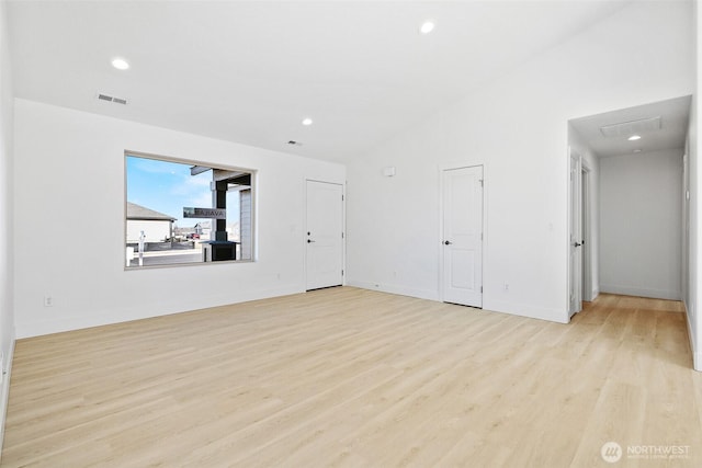 spare room with visible vents, baseboards, lofted ceiling, light wood-style flooring, and recessed lighting