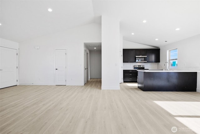 kitchen featuring light countertops, light wood-style flooring, decorative backsplash, appliances with stainless steel finishes, and a sink