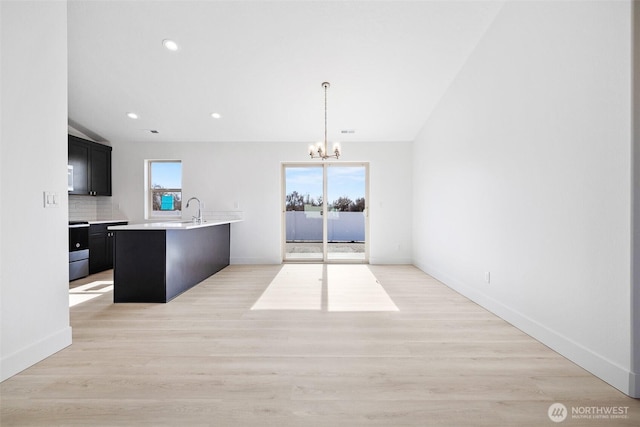 kitchen with plenty of natural light, tasteful backsplash, stove, dark cabinets, and light countertops