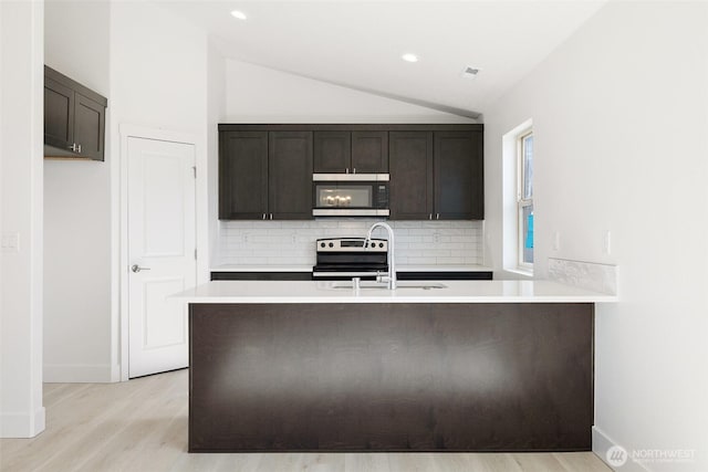 kitchen featuring lofted ceiling, stainless steel appliances, a sink, and light countertops