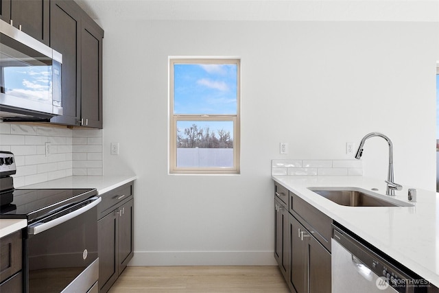 kitchen with light countertops, appliances with stainless steel finishes, a sink, and tasteful backsplash