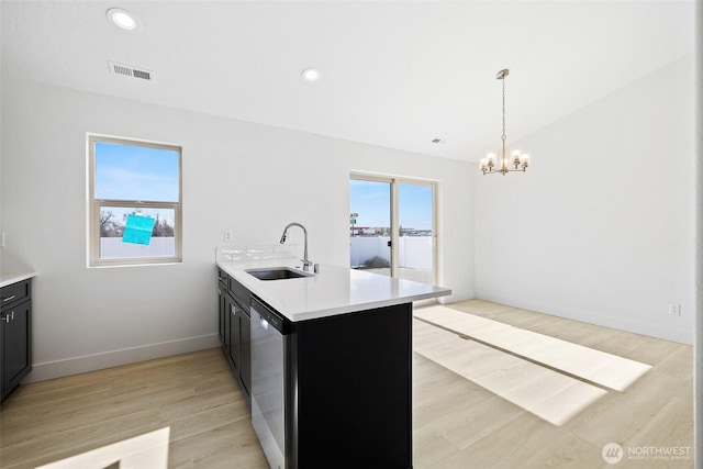 kitchen featuring dishwasher, a peninsula, a sink, and light countertops