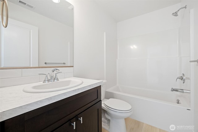 full bath featuring toilet, wood finished floors, vanity, visible vents, and  shower combination