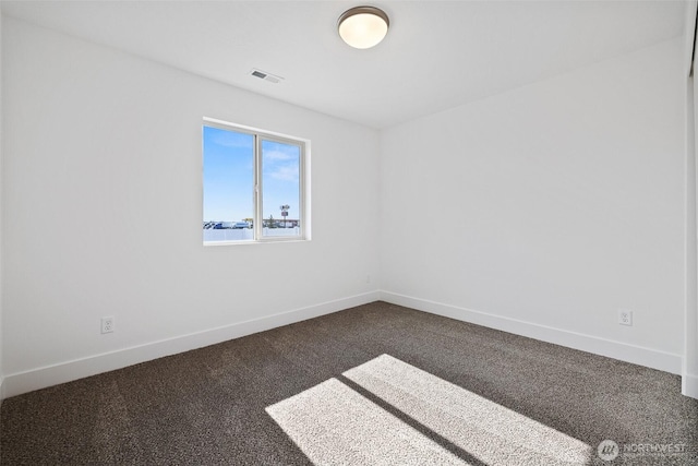 unfurnished room featuring dark colored carpet, visible vents, and baseboards