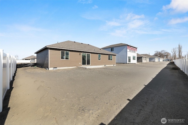 rear view of property featuring a fenced backyard and roof with shingles