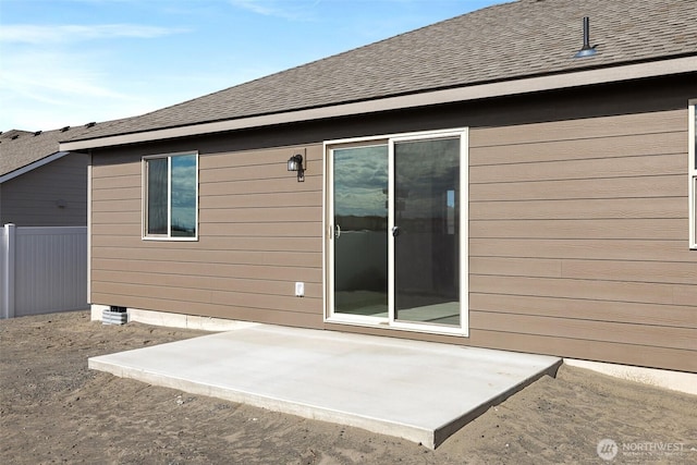 rear view of property featuring a shingled roof, fence, and a patio