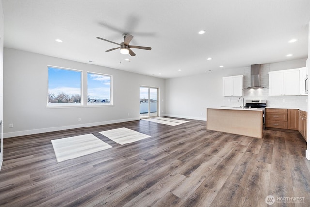 unfurnished living room featuring dark wood-style floors, recessed lighting, a sink, and baseboards