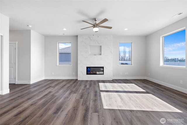 unfurnished living room with baseboards, a premium fireplace, visible vents, and a healthy amount of sunlight