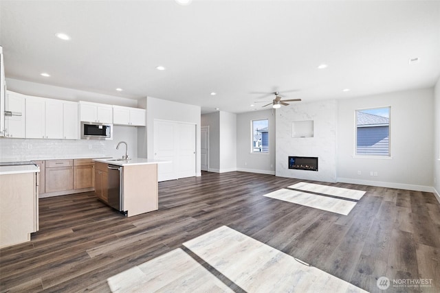 kitchen with tasteful backsplash, a premium fireplace, stainless steel appliances, light countertops, and a sink