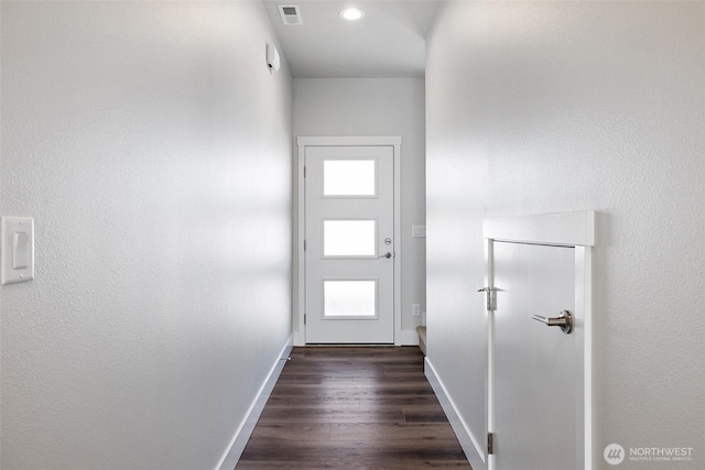 doorway to outside with dark wood-type flooring, visible vents, and baseboards