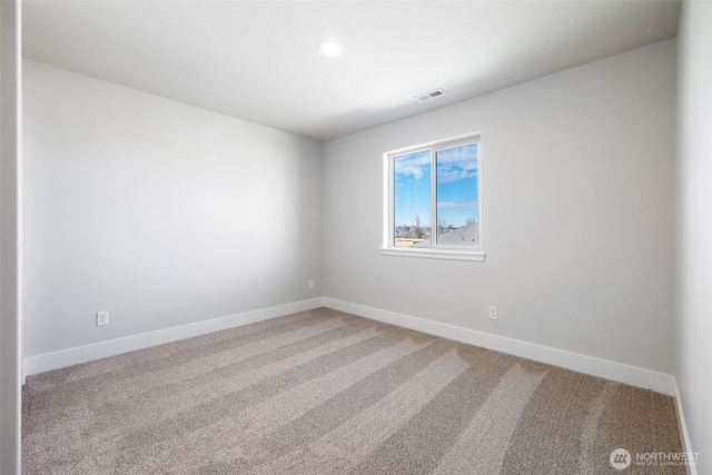 empty room with baseboards, visible vents, and light colored carpet