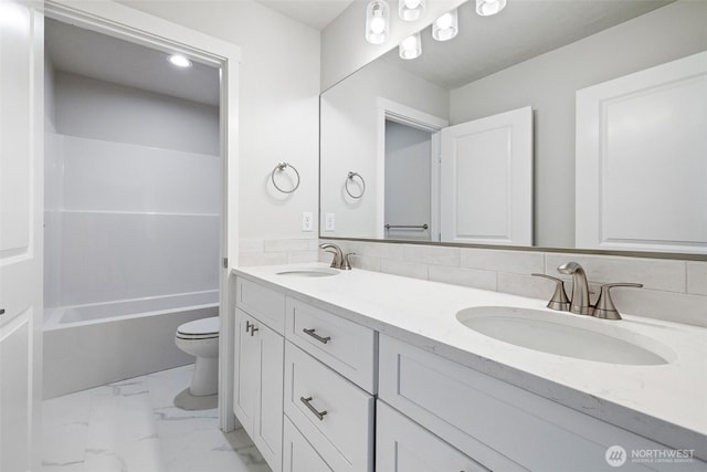 bathroom featuring marble finish floor, a sink, toilet, and double vanity