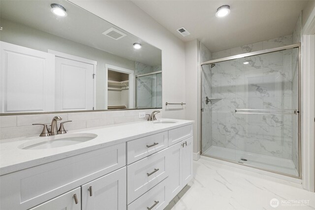 bathroom featuring marble finish floor, a marble finish shower, a sink, and visible vents