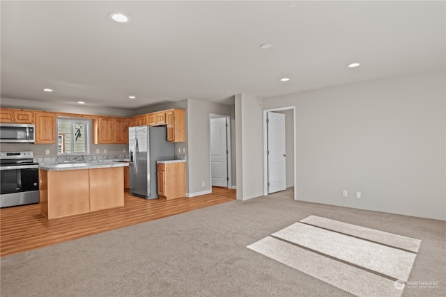 kitchen with stainless steel appliances, light hardwood / wood-style floors, a center island, and sink