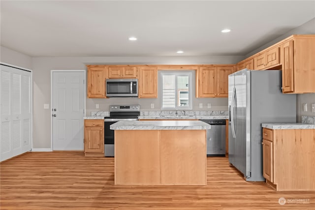 kitchen featuring light brown cabinetry, stainless steel appliances, sink, a kitchen island, and light hardwood / wood-style flooring