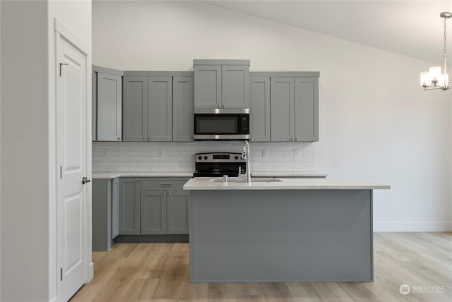 kitchen featuring gray cabinetry, sink, vaulted ceiling, decorative backsplash, and appliances with stainless steel finishes