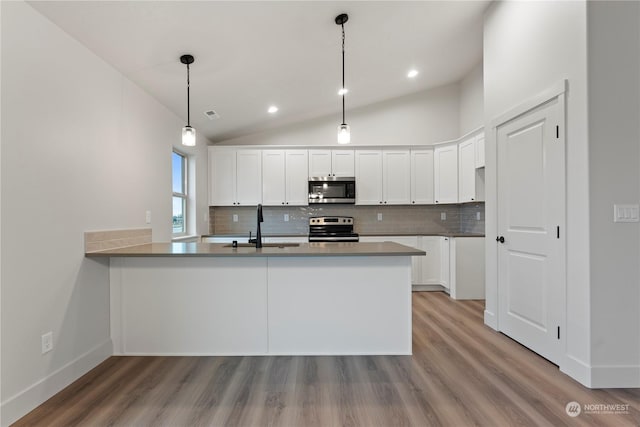 kitchen featuring kitchen peninsula, tasteful backsplash, stainless steel appliances, decorative light fixtures, and white cabinets