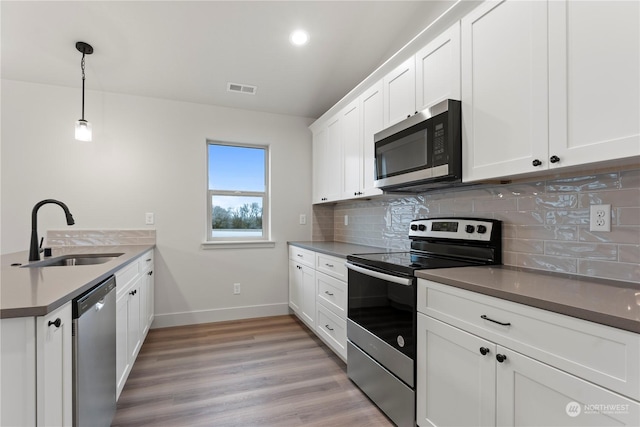 kitchen featuring pendant lighting, sink, light hardwood / wood-style flooring, appliances with stainless steel finishes, and white cabinetry