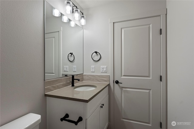 bathroom featuring decorative backsplash, toilet, and vanity