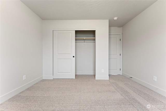 unfurnished bedroom with a closet and light colored carpet