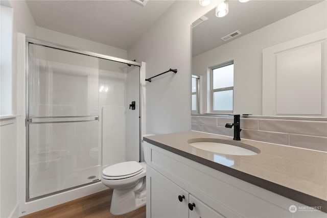 bathroom with hardwood / wood-style floors, vanity, a shower with door, and toilet